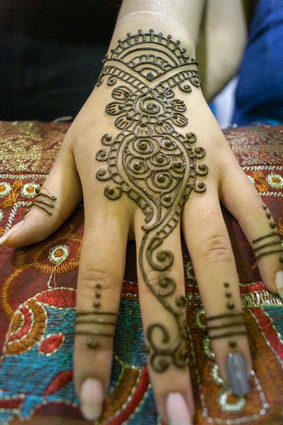 Diseño de mehendi elaborado con henna sobre la mano de una invitada