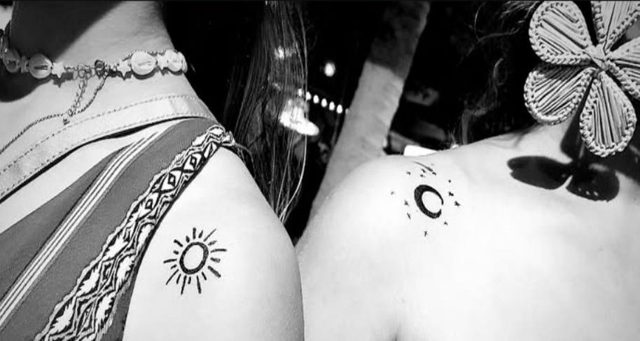 Tatuajes temporales pintados a mano con pincel sobre los hombros de dos invitadas